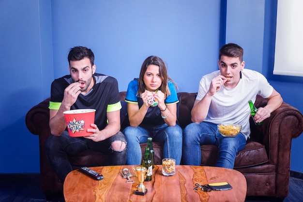 Amis regardant un match de football via IPTV avec du popcorn